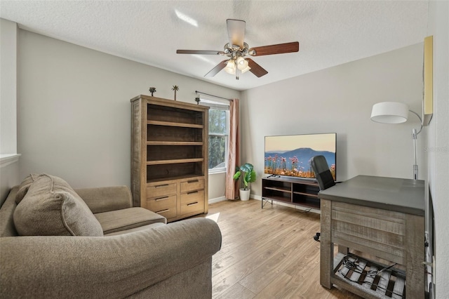 interior space featuring ceiling fan, a textured ceiling, and light hardwood / wood-style floors