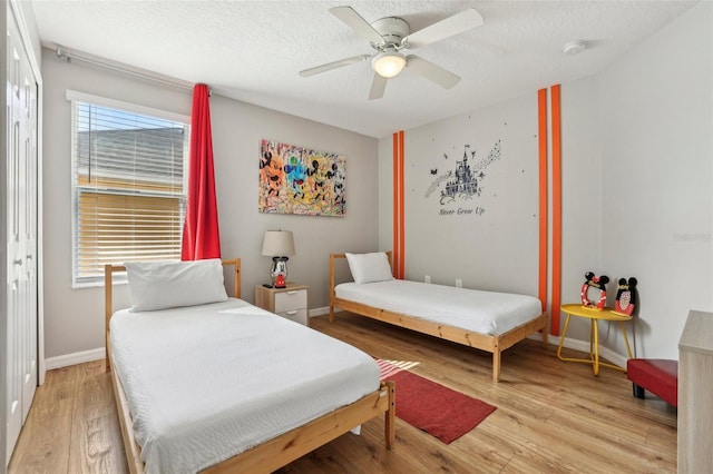 bedroom with ceiling fan, wood-type flooring, and a textured ceiling