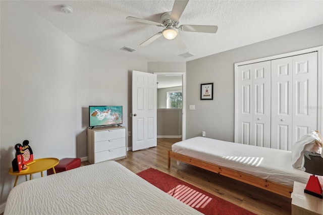 bedroom with a textured ceiling, a closet, ceiling fan, and light hardwood / wood-style flooring