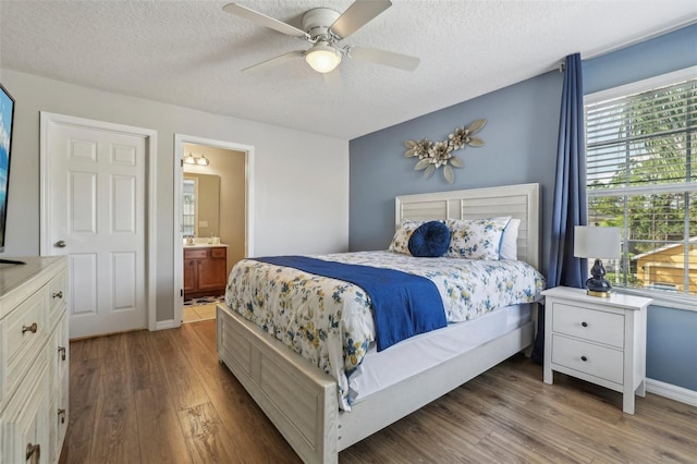 bedroom with ensuite bath, hardwood / wood-style flooring, ceiling fan, and a textured ceiling