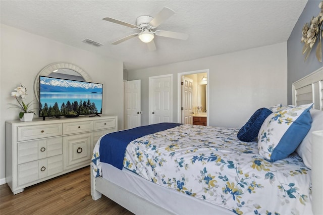 bedroom featuring ceiling fan, dark hardwood / wood-style floors, a textured ceiling, and ensuite bathroom