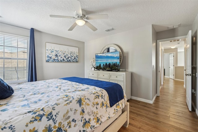 bedroom with ceiling fan, wood-type flooring, and a textured ceiling