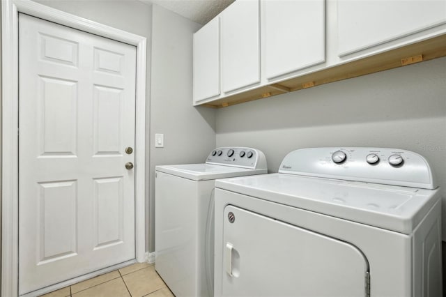 laundry room with washing machine and dryer, light tile patterned flooring, and cabinets