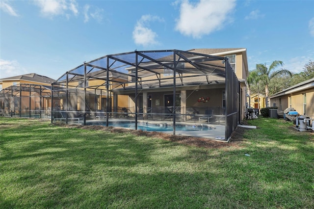 rear view of house with glass enclosure and a lawn