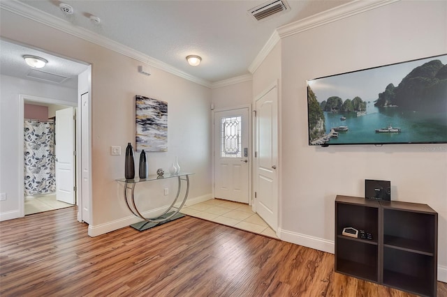 foyer entrance featuring ornamental molding, a textured ceiling, and light hardwood / wood-style flooring