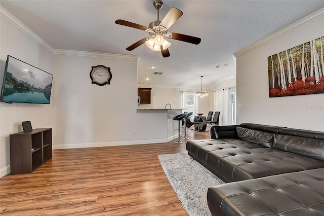 living room featuring crown molding, light hardwood / wood-style flooring, and a textured ceiling