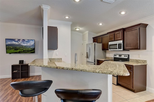 kitchen featuring crown molding, stainless steel appliances, a kitchen breakfast bar, and kitchen peninsula