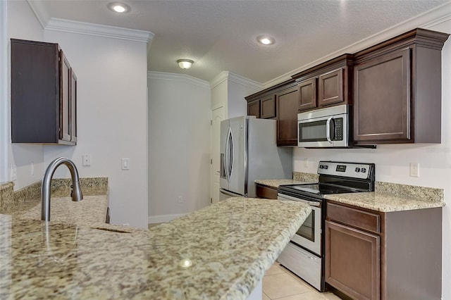 kitchen with light tile patterned flooring, appliances with stainless steel finishes, ornamental molding, dark brown cabinets, and a textured ceiling