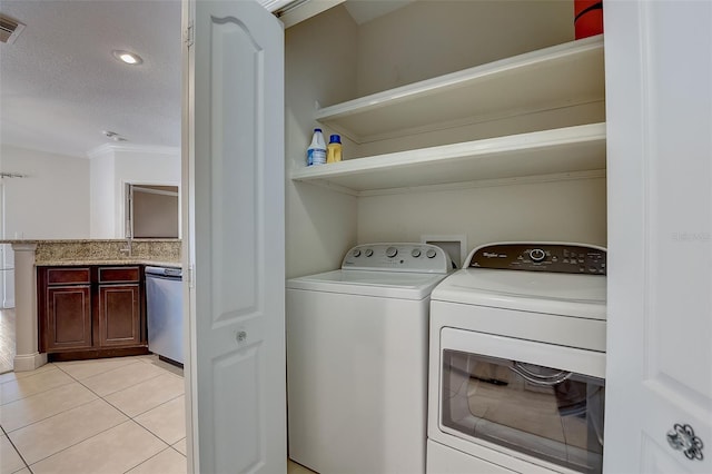 clothes washing area with light tile patterned flooring, washer and dryer, and a textured ceiling