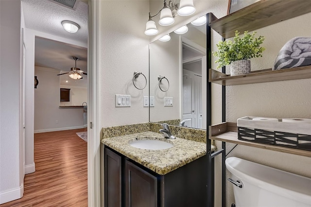 bathroom with hardwood / wood-style flooring, ceiling fan, vanity, ornamental molding, and toilet