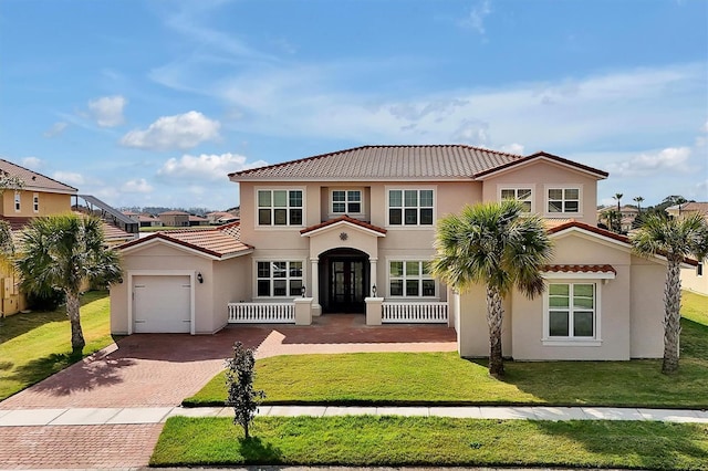 mediterranean / spanish-style home featuring decorative driveway, stucco siding, an attached garage, a tiled roof, and a front lawn