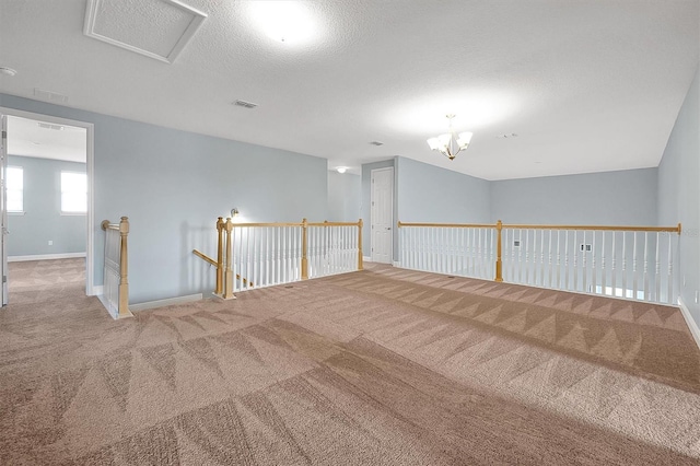 spare room with baseboards, visible vents, a textured ceiling, carpet floors, and a notable chandelier