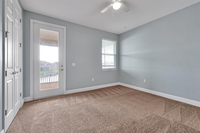 carpeted empty room featuring ceiling fan and baseboards