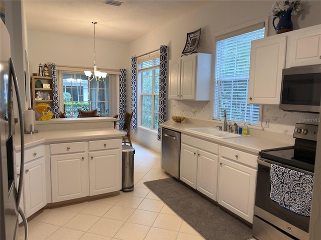 kitchen with white cabinetry, stainless steel appliances, decorative light fixtures, and sink