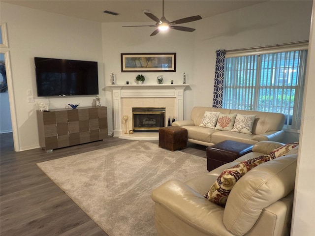 living room with hardwood / wood-style flooring, a tiled fireplace, and ceiling fan