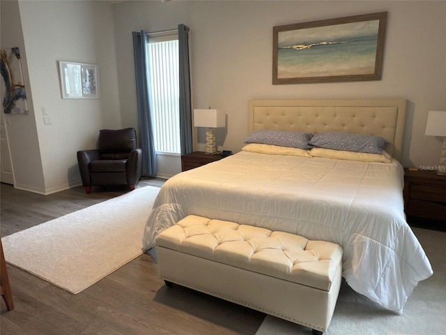 bedroom with multiple windows and dark hardwood / wood-style floors