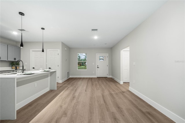 kitchen with visible vents, light countertops, gray cabinetry, pendant lighting, and a sink