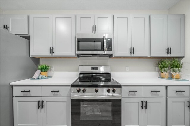 kitchen featuring stainless steel appliances, light countertops, and white cabinetry