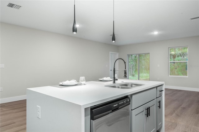 kitchen featuring a sink, a center island with sink, light countertops, and stainless steel dishwasher