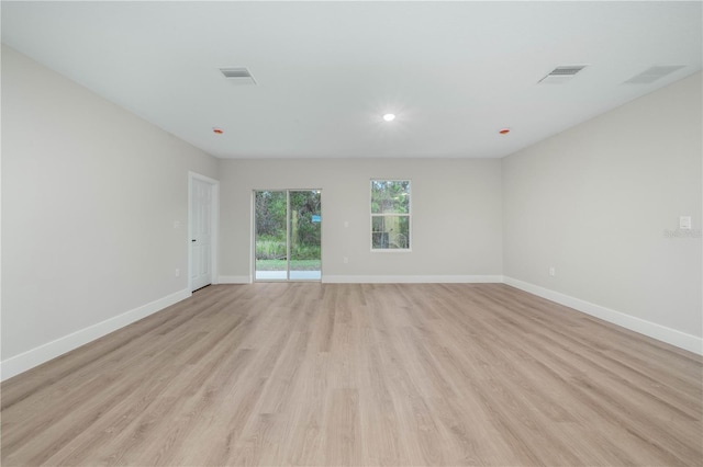 unfurnished room featuring visible vents, light wood-style flooring, and baseboards