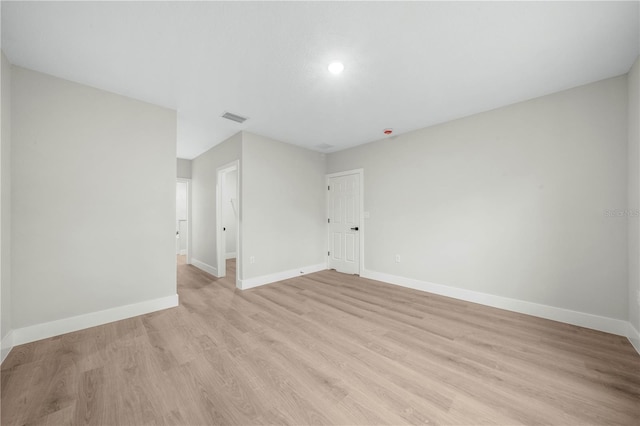 spare room with light wood-style floors, visible vents, and baseboards