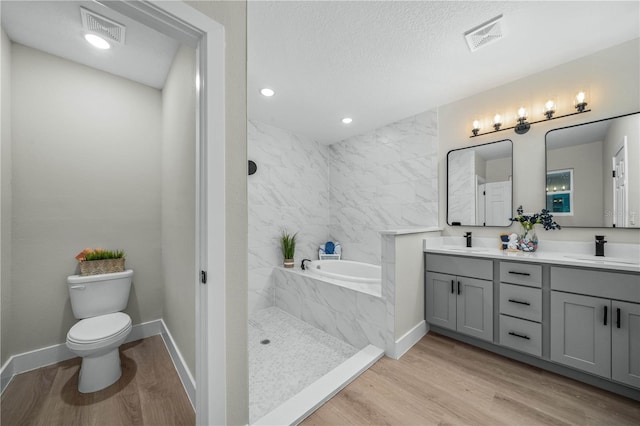 bathroom featuring a garden tub, a sink, visible vents, and wood finished floors