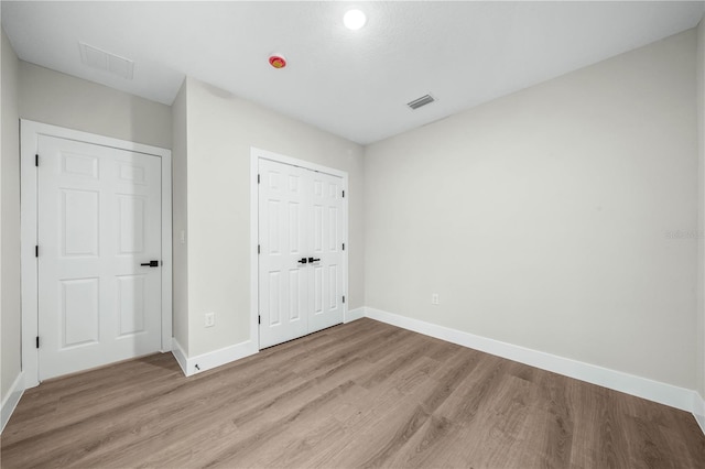 unfurnished bedroom with baseboards, a closet, visible vents, and light wood-style floors