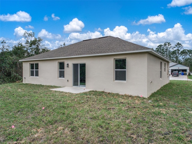 rear view of property featuring stucco siding, roof with shingles, a lawn, and a patio