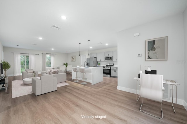 living area with light wood-style floors, baseboards, visible vents, and recessed lighting