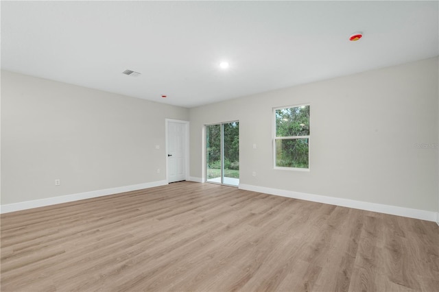 empty room featuring light wood-style floors, visible vents, and baseboards