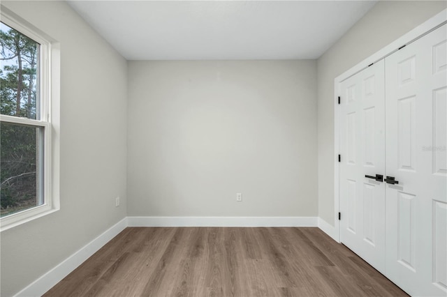 unfurnished bedroom featuring a closet, baseboards, and wood finished floors