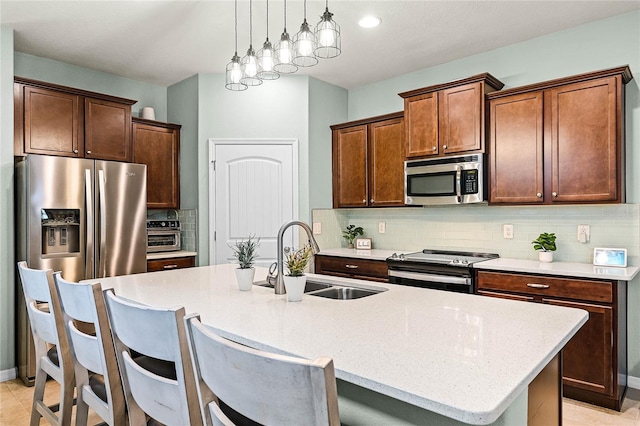 kitchen featuring tasteful backsplash, an island with sink, stainless steel appliances, a kitchen bar, and a sink