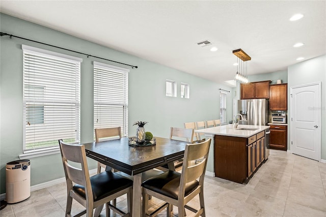 kitchen featuring visible vents, decorative light fixtures, a kitchen island with sink, stainless steel appliances, and light countertops