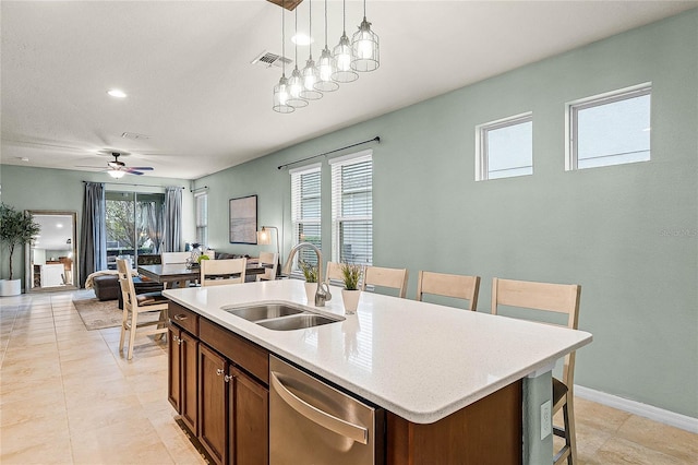 kitchen with pendant lighting, a center island with sink, light countertops, a sink, and dishwasher