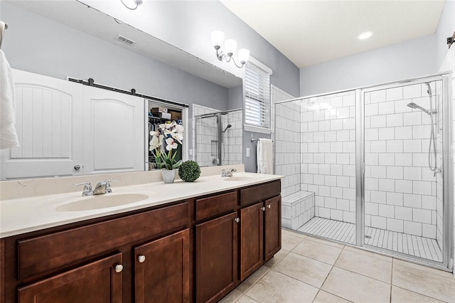 bathroom featuring double vanity, a stall shower, visible vents, tile patterned flooring, and a sink