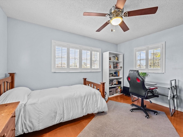 bedroom featuring light wood-type flooring, ceiling fan, and a textured ceiling