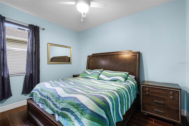 bedroom with a ceiling fan, wood tiled floor, a textured ceiling, and baseboards