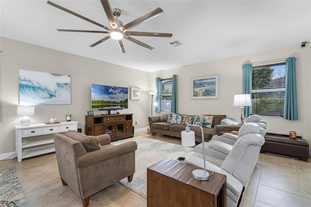 living area featuring a ceiling fan, visible vents, baseboards, and light tile patterned floors
