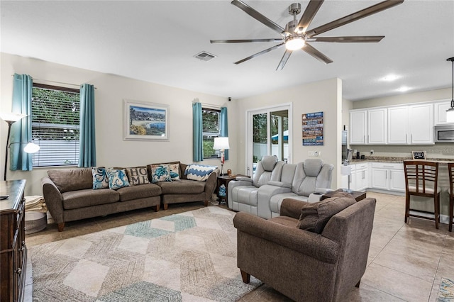 living room with a ceiling fan, light tile patterned flooring, and visible vents