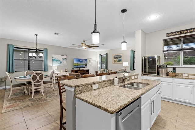 kitchen featuring stainless steel dishwasher, a sink, white cabinetry, and decorative light fixtures