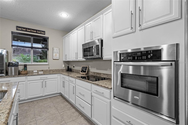 kitchen featuring appliances with stainless steel finishes, light tile patterned flooring, light stone countertops, and white cabinets