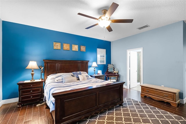 bedroom featuring visible vents, baseboards, a ceiling fan, wood tiled floor, and a textured ceiling