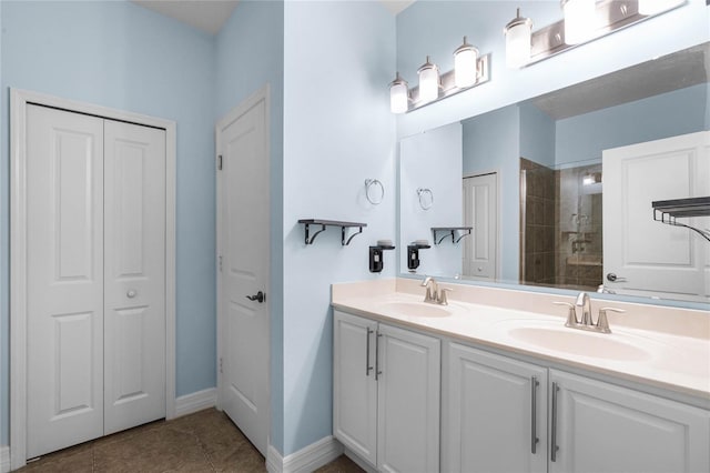 bathroom featuring a closet, tiled shower, a sink, and double vanity