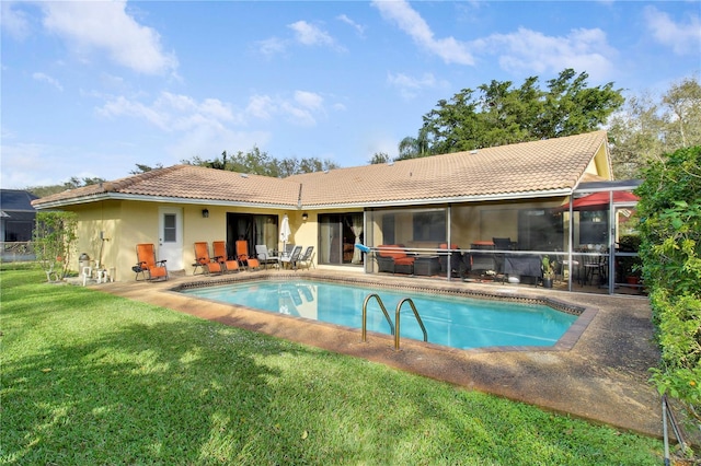 back of house featuring a lawn, a sunroom, and a patio