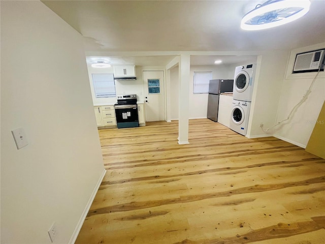 interior space featuring an AC wall unit, light hardwood / wood-style floors, and stacked washer and clothes dryer