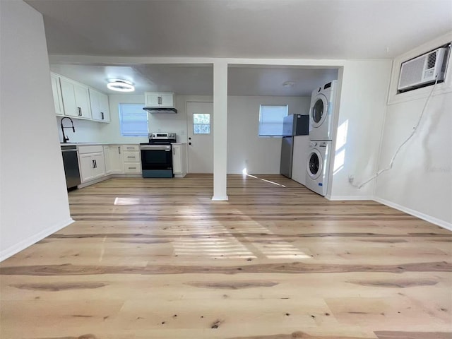 kitchen featuring white cabinetry, light wood-style floors, light countertops, appliances with stainless steel finishes, and stacked washing maching and dryer