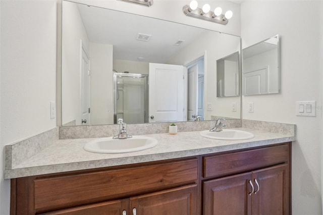 full bath with double vanity, a sink, visible vents, and a shower stall