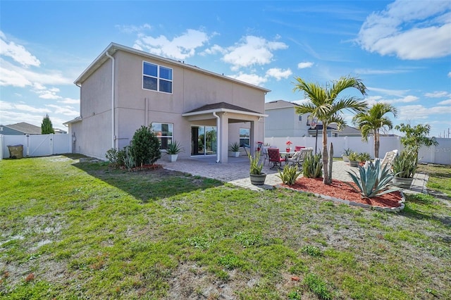 rear view of house with a patio, stucco siding, a lawn, a gate, and a fenced backyard