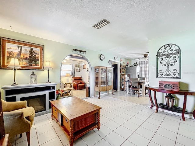 tiled living room with ceiling fan and a textured ceiling