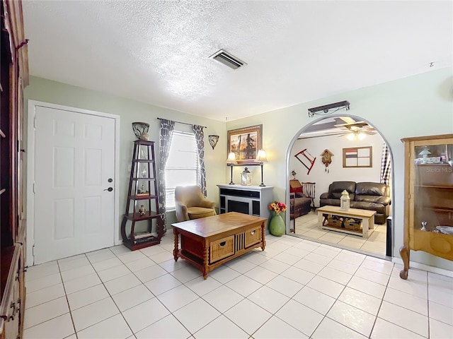 tiled entryway with ceiling fan and a textured ceiling